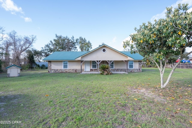 single story home with stucco siding, an outbuilding, stone siding, a shed, and a front yard