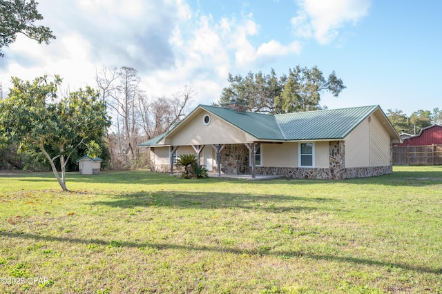 ranch-style house featuring stone siding, a storage shed, an outbuilding, and a front lawn