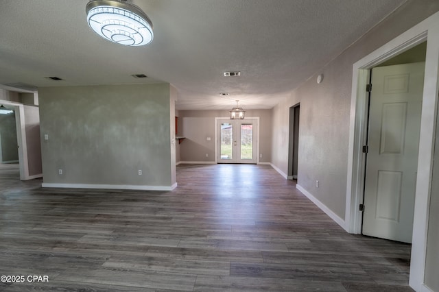 empty room with french doors, a textured ceiling, visible vents, and dark wood-style flooring