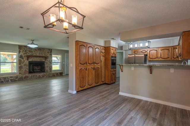 kitchen featuring visible vents, open floor plan, appliances with stainless steel finishes, a peninsula, and brown cabinetry