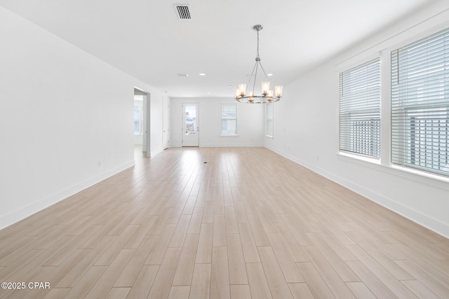 unfurnished room featuring light wood-style floors, visible vents, baseboards, and a notable chandelier