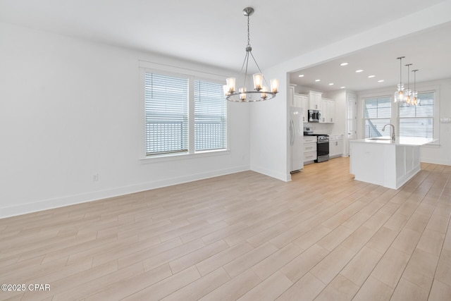 interior space with light wood-type flooring, a notable chandelier, a sink, recessed lighting, and baseboards