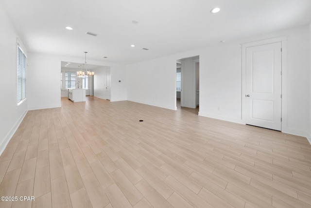 unfurnished living room with baseboards, visible vents, light wood finished floors, recessed lighting, and a chandelier