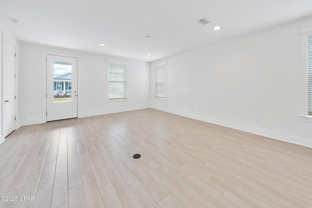 empty room featuring light wood finished floors, visible vents, recessed lighting, and baseboards