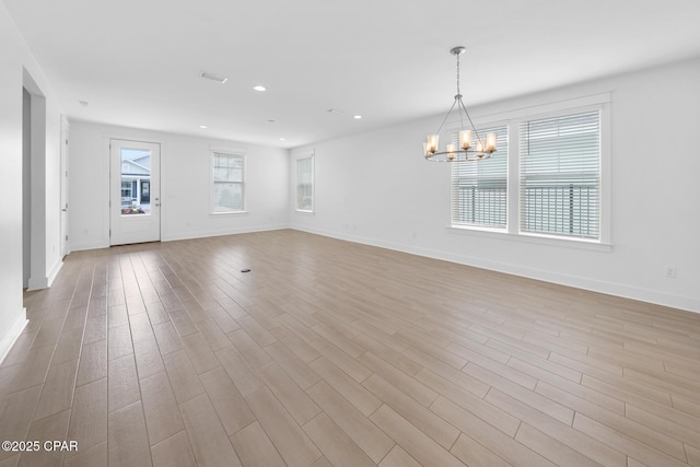 spare room with wood finished floors, baseboards, visible vents, an inviting chandelier, and recessed lighting