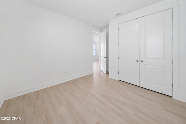 unfurnished bedroom featuring a closet, baseboards, visible vents, and light wood finished floors