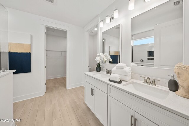 2009 Calamint St, Panama City, FL 32405 - bathroom featuring double vanity, a shower, wood finished floors, a walk in closet, and baseboards