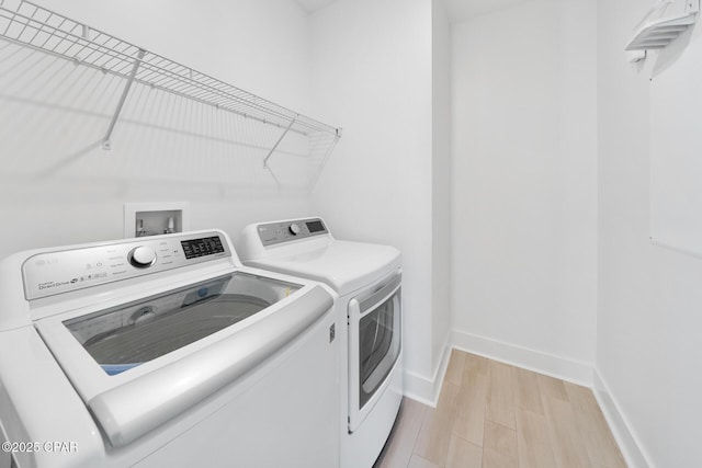 laundry area with washer and clothes dryer, laundry area, light wood-type flooring, and baseboards