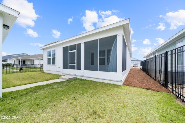 rear view of house with a lawn, fence, and a sunroom