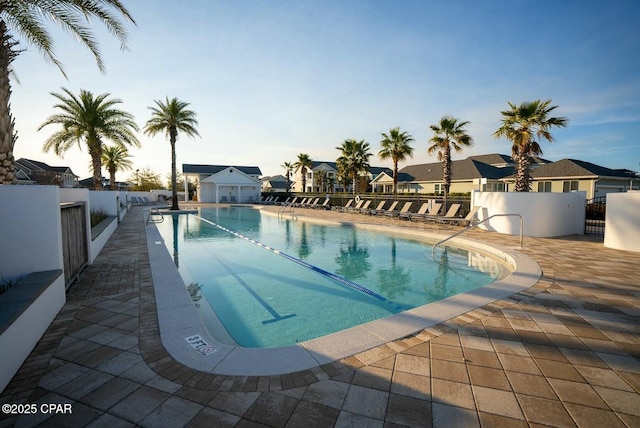 pool featuring a patio, fence, a residential view, and an outbuilding