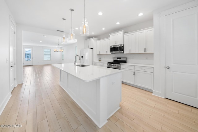 kitchen with a notable chandelier, stainless steel appliances, wood tiled floor, and a sink