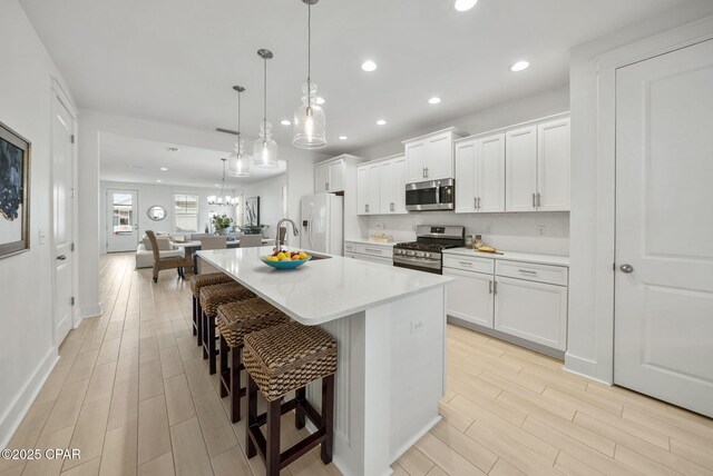 2009 Calamint St, Panama City, FL 32405 - kitchen with stainless steel appliances, an island with sink, a breakfast bar area, light wood-type flooring, and light countertops