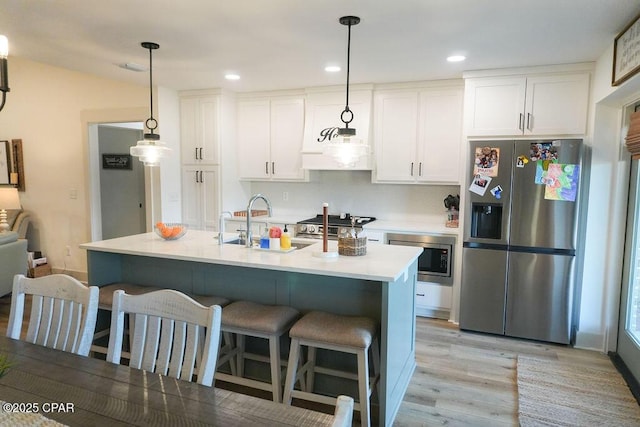 kitchen featuring appliances with stainless steel finishes, a breakfast bar area, white cabinets, and light countertops