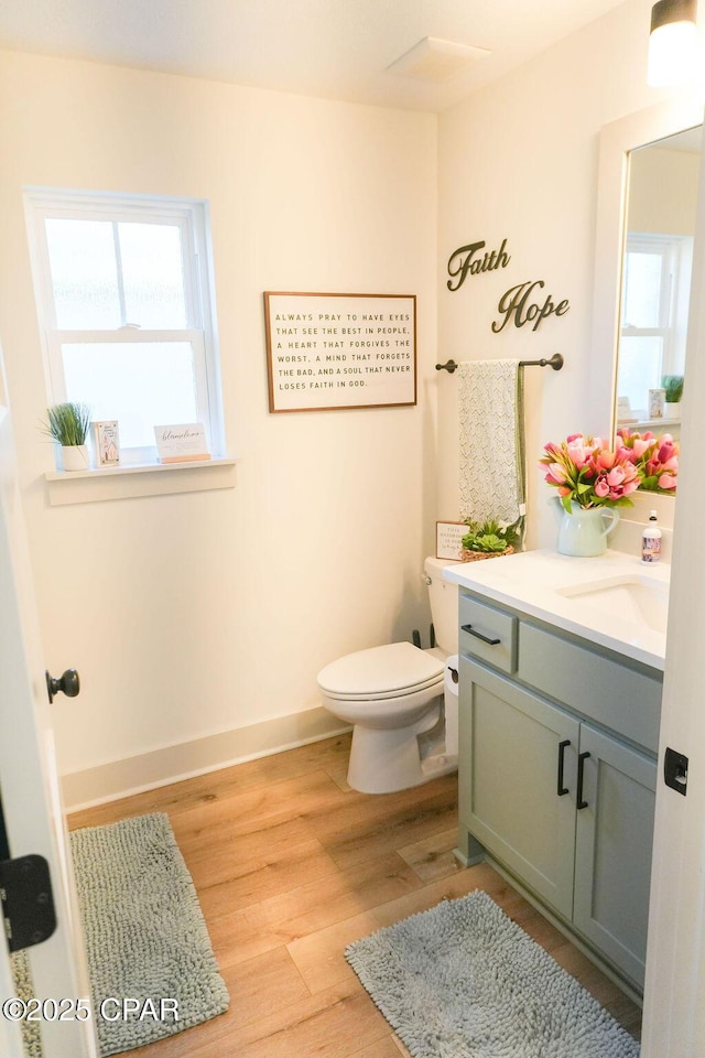 bathroom with baseboards, toilet, wood finished floors, and vanity