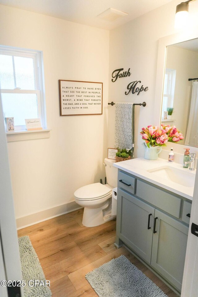 full bathroom featuring toilet, vanity, baseboards, and wood finished floors