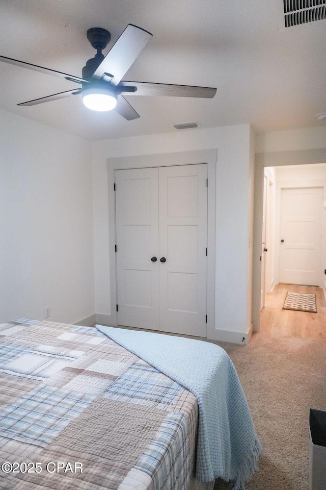 bedroom featuring visible vents, light carpet, a ceiling fan, a closet, and baseboards