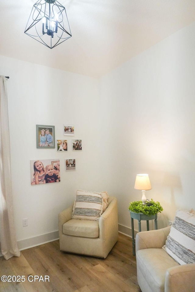 living area with baseboards, a notable chandelier, and wood finished floors