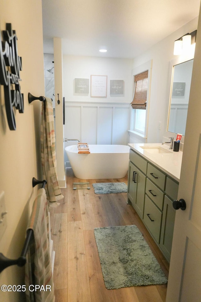 full bath with vanity, hardwood / wood-style floors, a freestanding tub, walk in shower, and a decorative wall