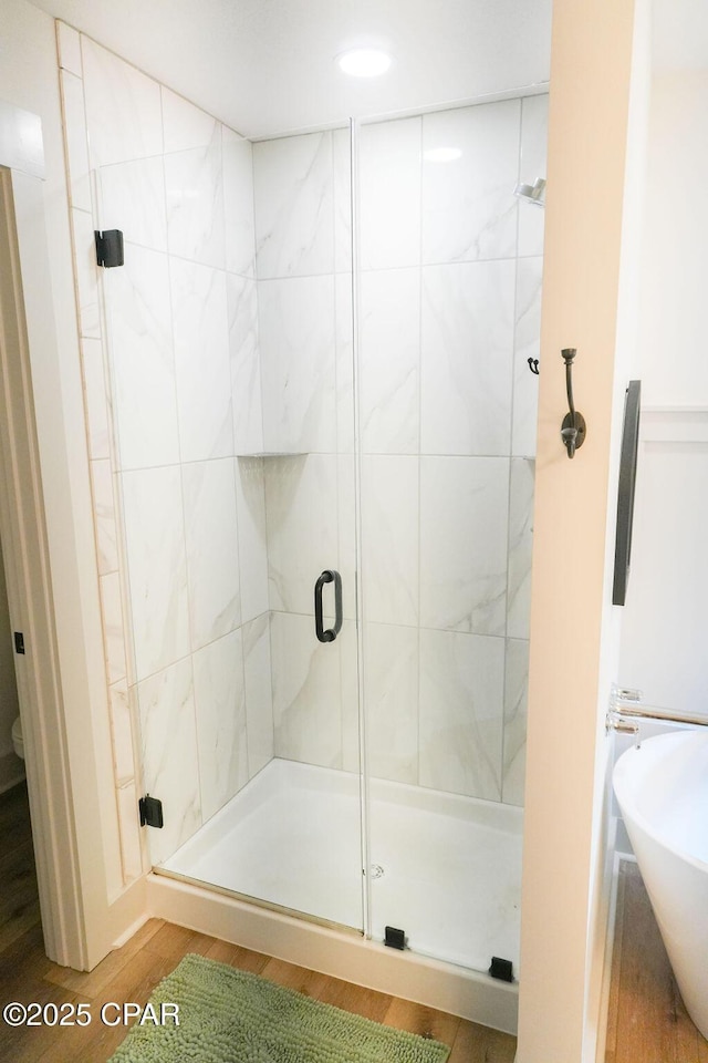 full bathroom featuring a sink, a shower stall, and wood finished floors