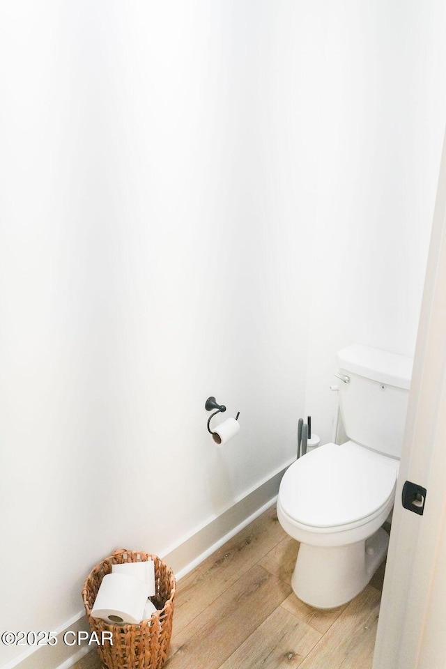 bathroom with toilet, wood finished floors, and baseboards