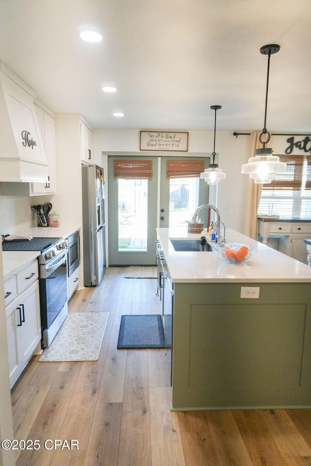 kitchen with a sink, light wood-style flooring, appliances with stainless steel finishes, and white cabinets