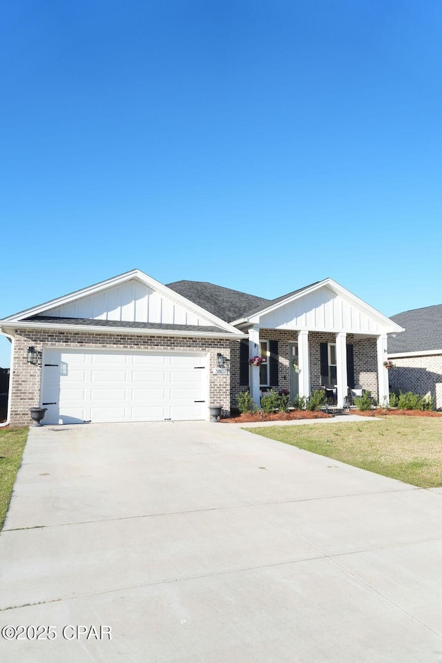 view of front of house featuring board and batten siding, concrete driveway, a front yard, a garage, and brick siding