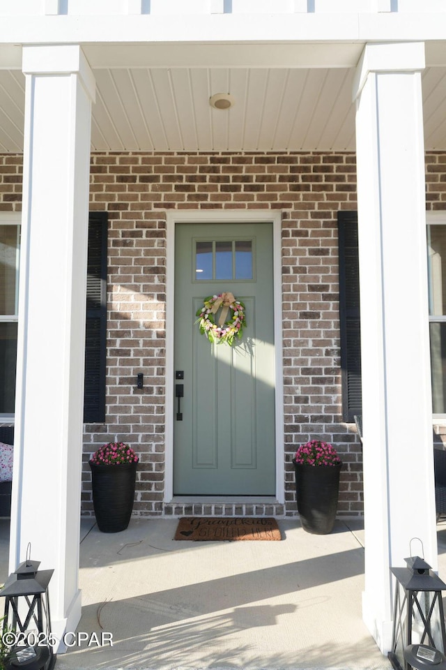 property entrance with a porch and brick siding