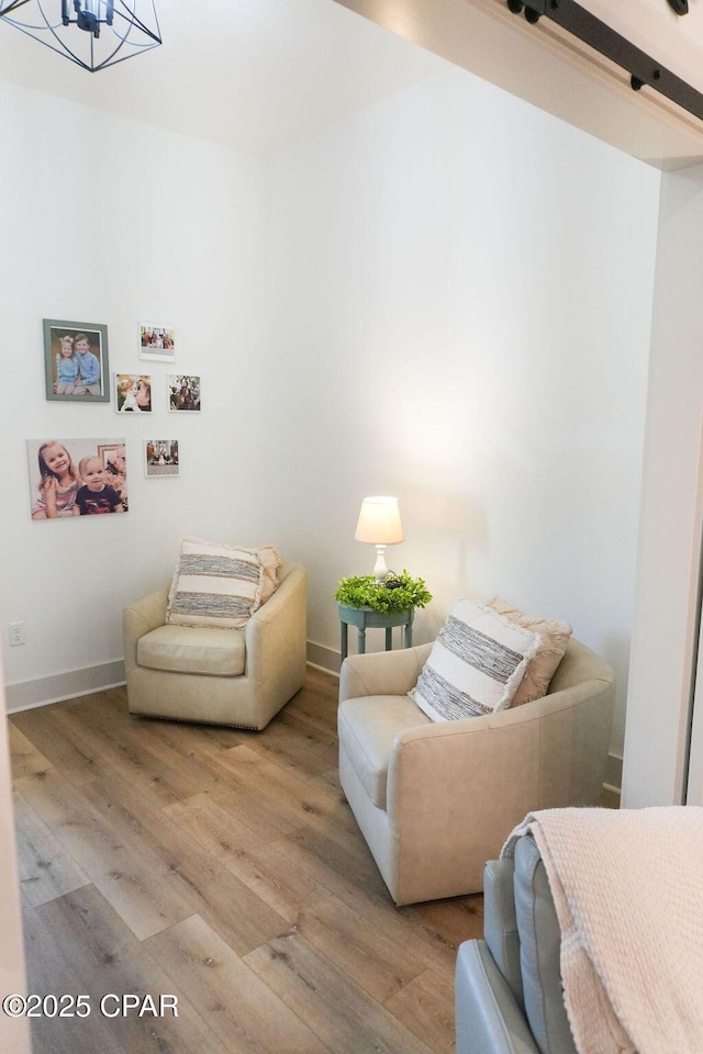 living area featuring a notable chandelier, baseboards, and wood finished floors