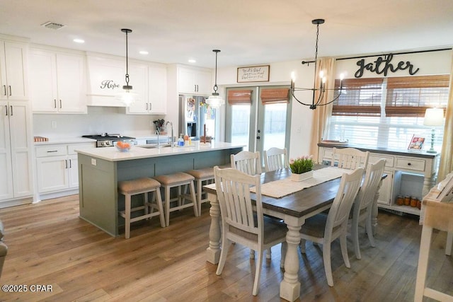 dining space with light wood-style flooring, recessed lighting, french doors, and visible vents