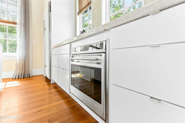 239 Sand Oaks Cir, Santa Rosa Beach, FL 32459 - kitchen with light wood-style flooring, modern cabinets, white cabinets, and oven