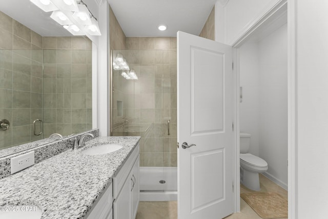 full bath featuring baseboards, a shower stall, vanity, and toilet