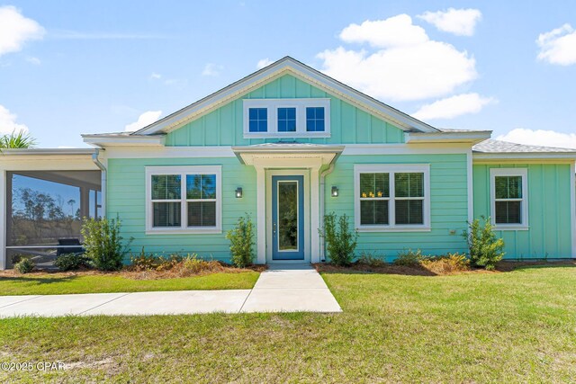 view of front of home featuring board and batten siding, a front lawn, and a sunroom