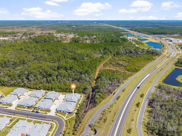 drone / aerial view featuring a wooded view and a water view