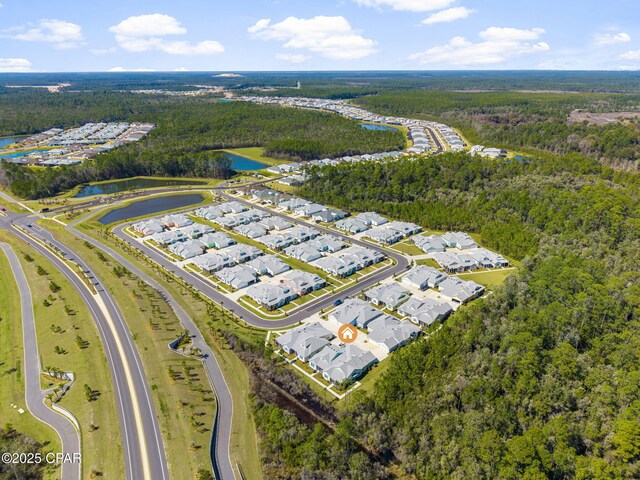 drone / aerial view with a view of trees, a water view, and a residential view