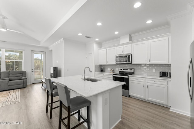 kitchen with decorative backsplash, light wood-type flooring, appliances with stainless steel finishes, and a sink