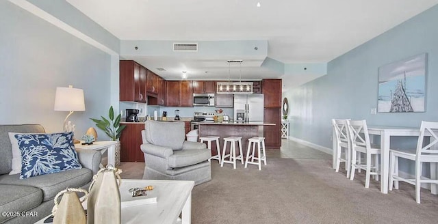 living room with visible vents, baseboards, and light colored carpet