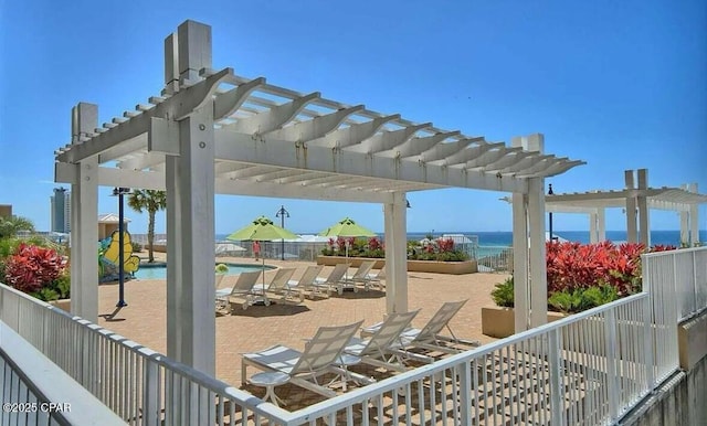 view of patio / terrace featuring a community pool, fence, a water view, and a pergola