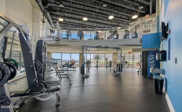 workout area with baseboards and a towering ceiling