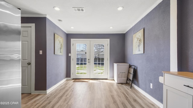 entryway with visible vents, baseboards, ornamental molding, french doors, and light wood-style floors