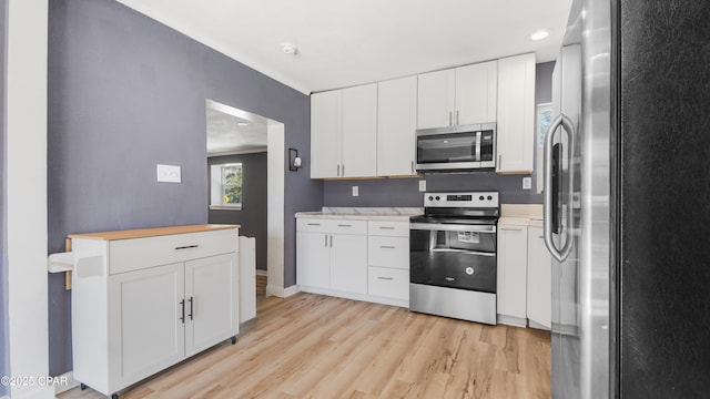 kitchen featuring stainless steel appliances, light wood-style floors, white cabinets, light countertops, and baseboards