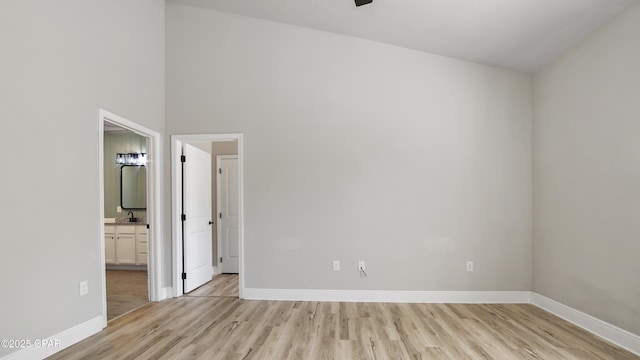 empty room featuring a sink, light wood-type flooring, and baseboards