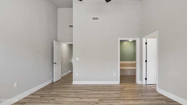 unfurnished bedroom with visible vents, baseboards, ensuite bath, and light wood finished floors