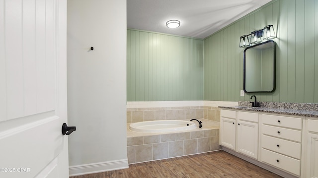 bathroom featuring a garden tub, wood finished floors, and vanity