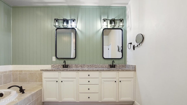 full bath with double vanity, a garden tub, and a sink