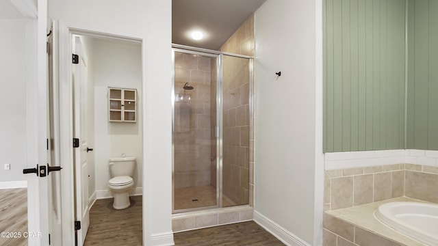 bathroom featuring baseboards, toilet, wood finished floors, and a shower stall