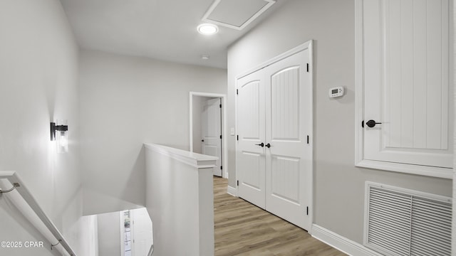 hallway featuring visible vents, baseboards, attic access, recessed lighting, and light wood-style floors