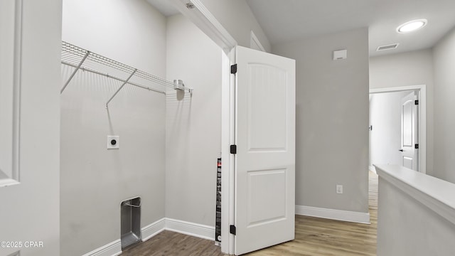 laundry area with electric dryer hookup, visible vents, light wood-style floors, baseboards, and laundry area