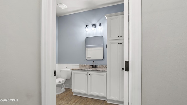 bathroom featuring toilet, wood finished floors, and vanity