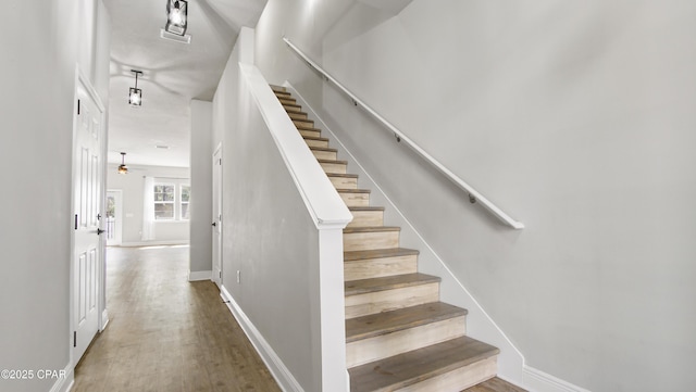 staircase with baseboards and wood finished floors