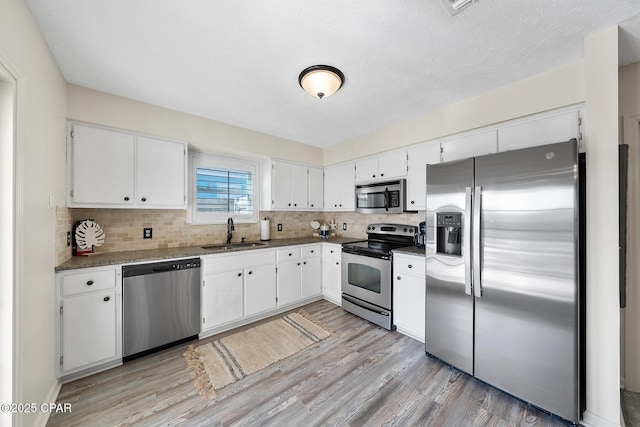 kitchen with a sink, white cabinets, light wood-type flooring, and stainless steel appliances